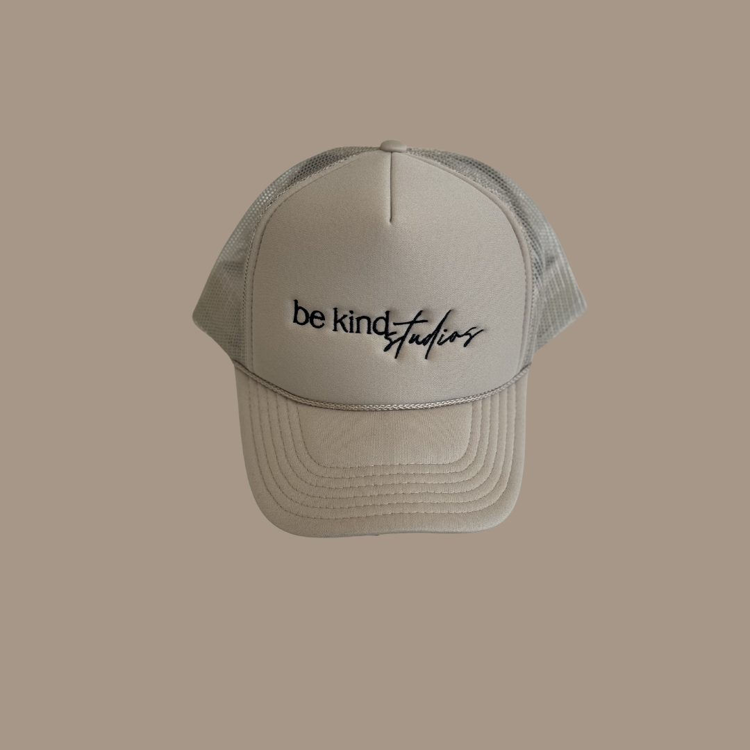 Trucker hat with the words "be kind studios" embroidered on the front.