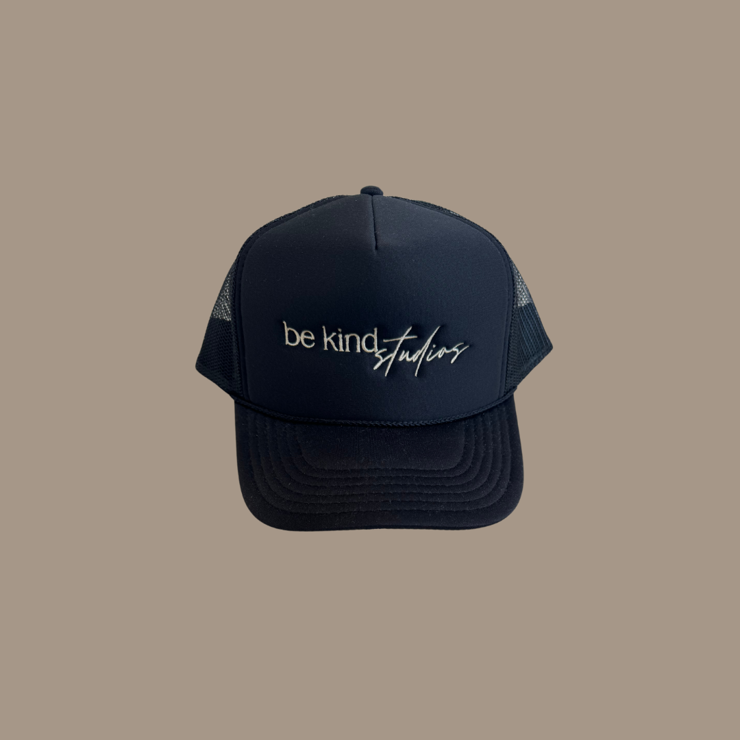 Trucker hat with the words "be kind studios" embroidered on the front.