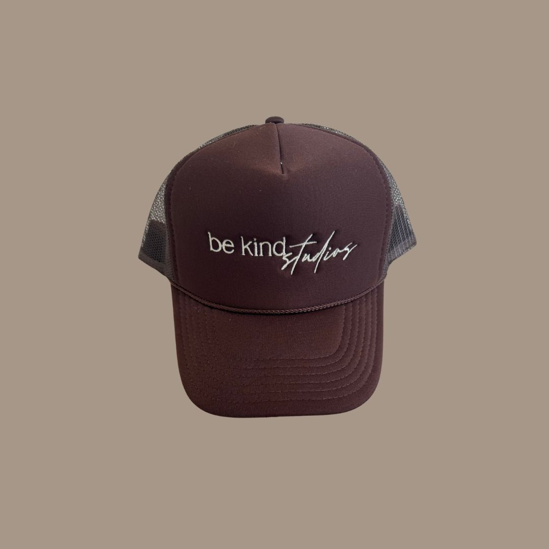 Trucker hat with the words "be kind studios" embroidered on the front.